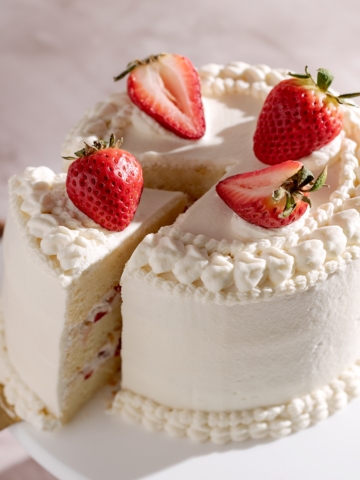 Strawberry chiffon cake with a slice cut out of it.