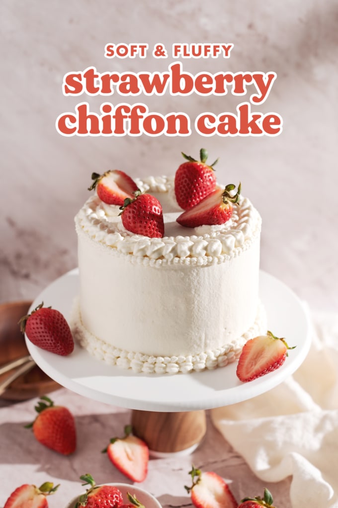 Cake covered in whipped cream and strawberries on a cake stand.