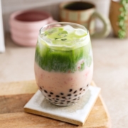 Glass filled with boba pearls, strawberry milk, and matcha split into two layers.
