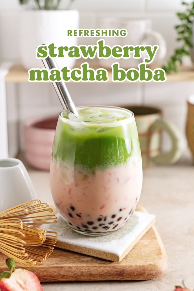 Strawberry matcha boba in a glass with straw and matcha whisk on the side.
