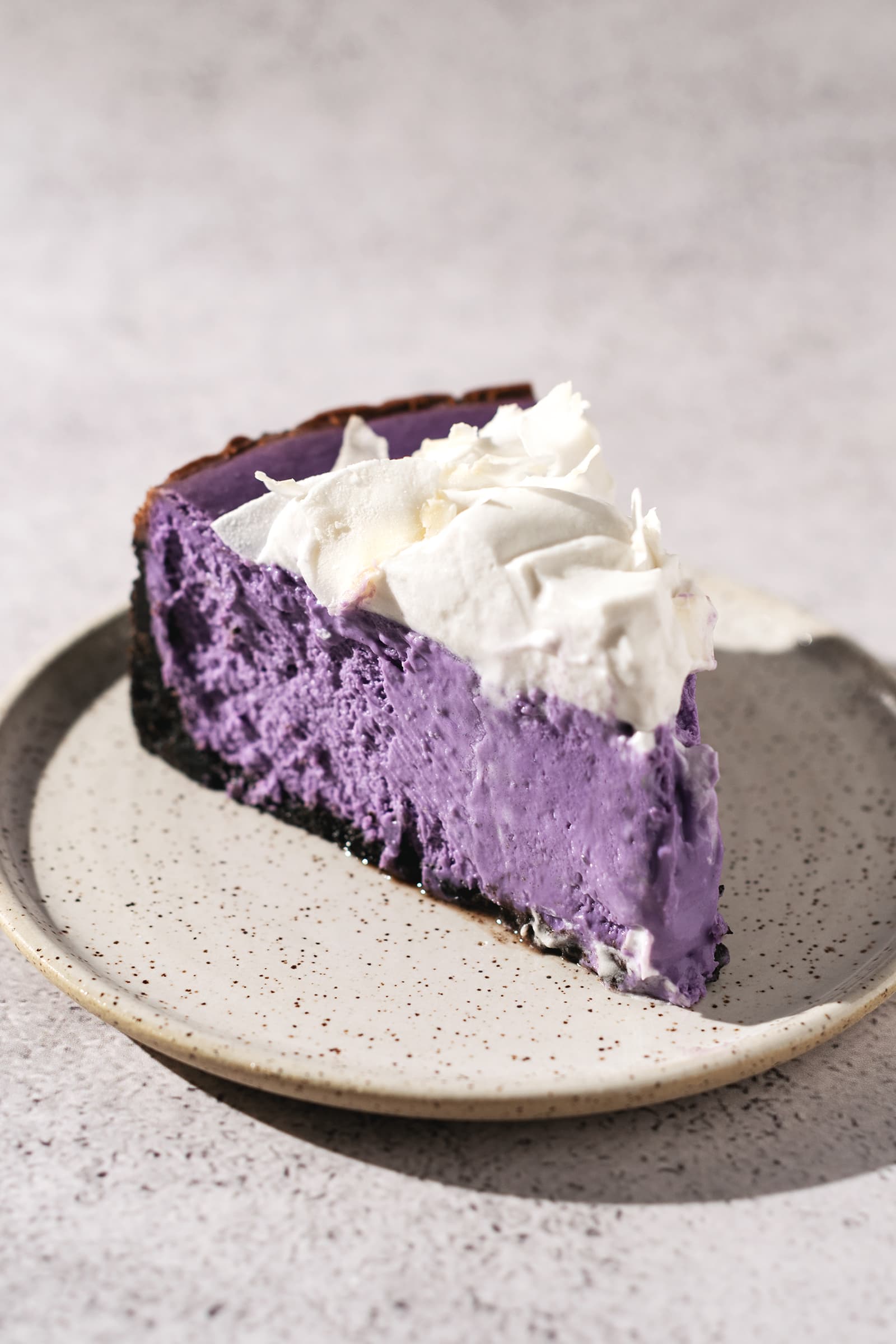 A single slice of ube cheesecake on a plate.