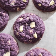 Ube cookie with white chocolate chunks on parchment paper.