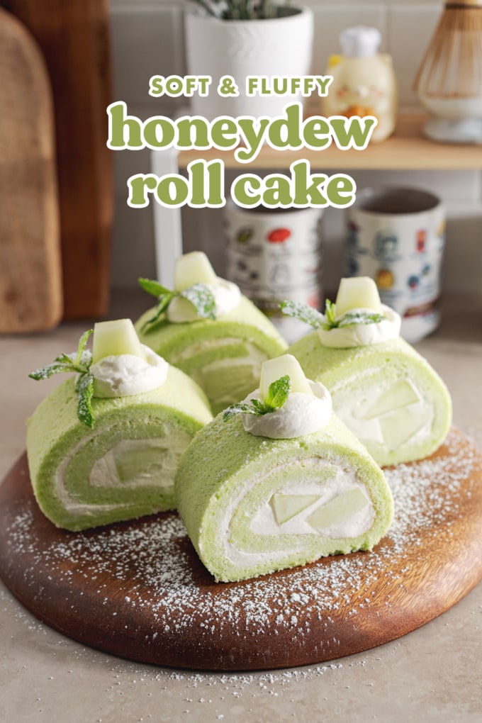 Four slices of honeydew roll cake sprinkled with powdered sugar on a wooden platter.