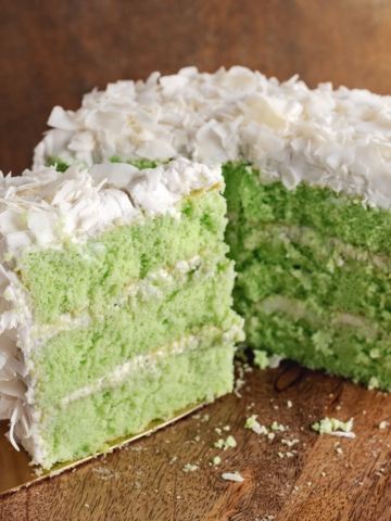 A slice of pandan coconut cake in front of half of a cake in the background.