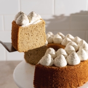 Lifting a slice of earl grey chiffon cake from the rest of the cake on a cake stand.