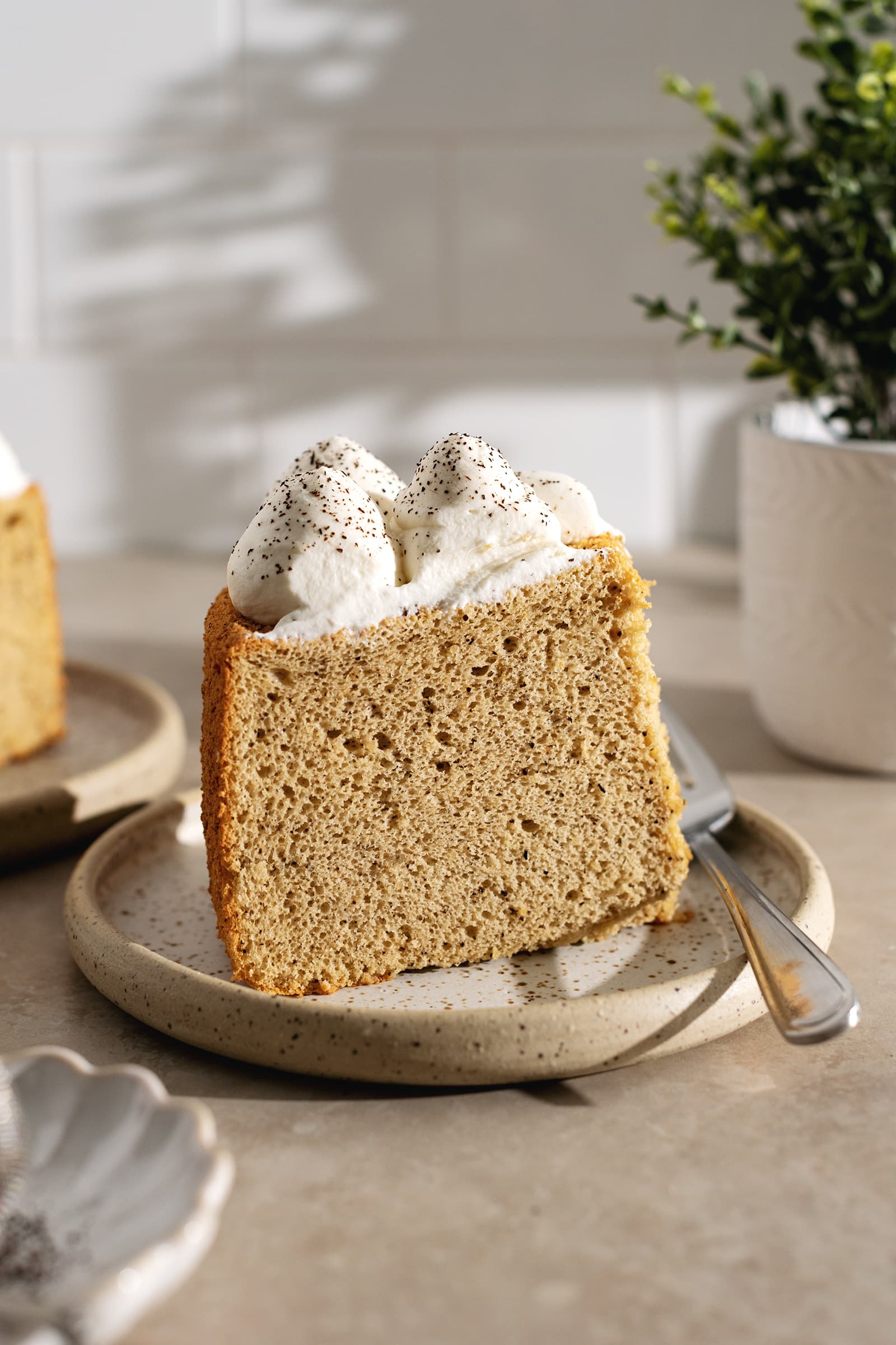 A slice of earl grey chiffon cake on a plate with a fork.
