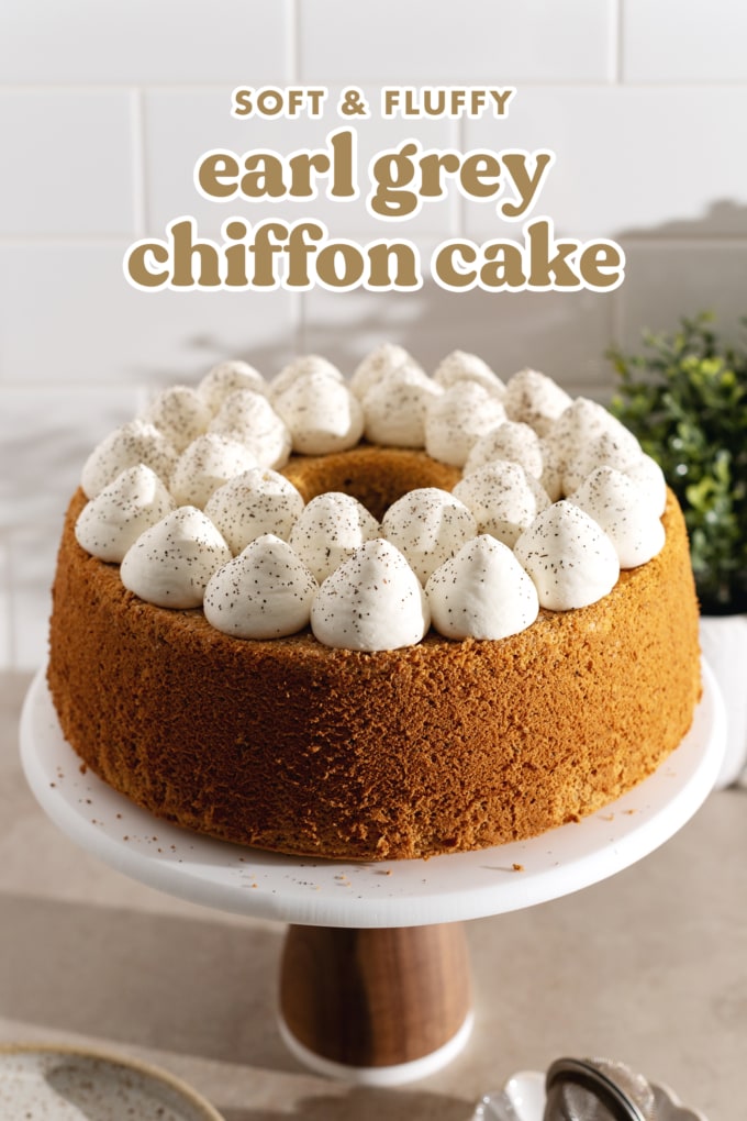A chiffon cake topped with dollops of whipped cream on a cake stand.