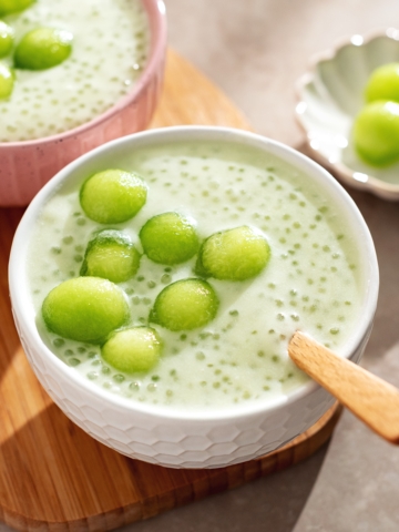 A bowl of honeydew sago pudding with honeydew melon balls on top.