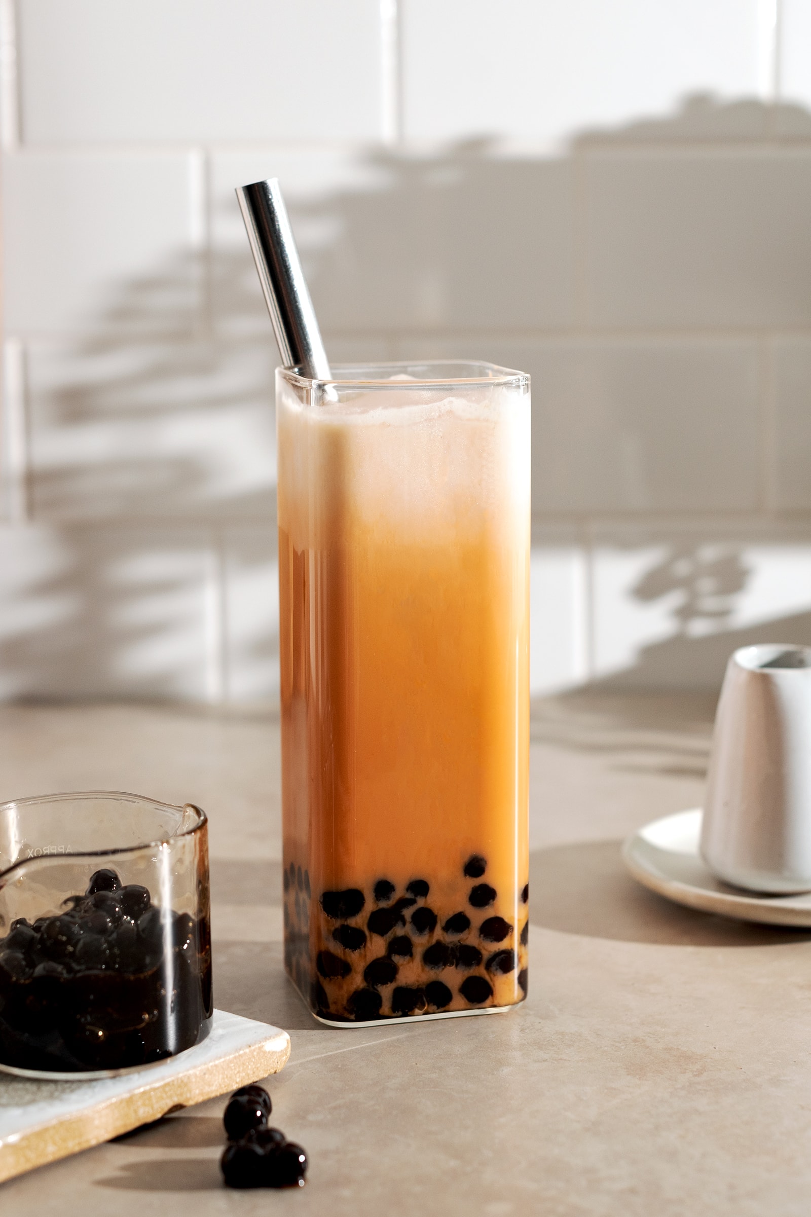 Thai milk tea boba in a rectangular glass with metal straw.