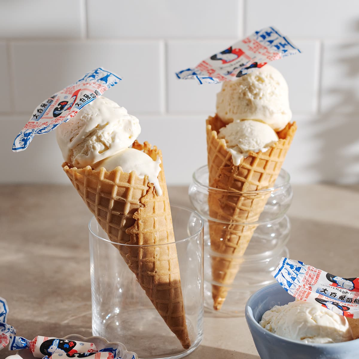 Two white rabbit ice cream cones standing up in glasses.