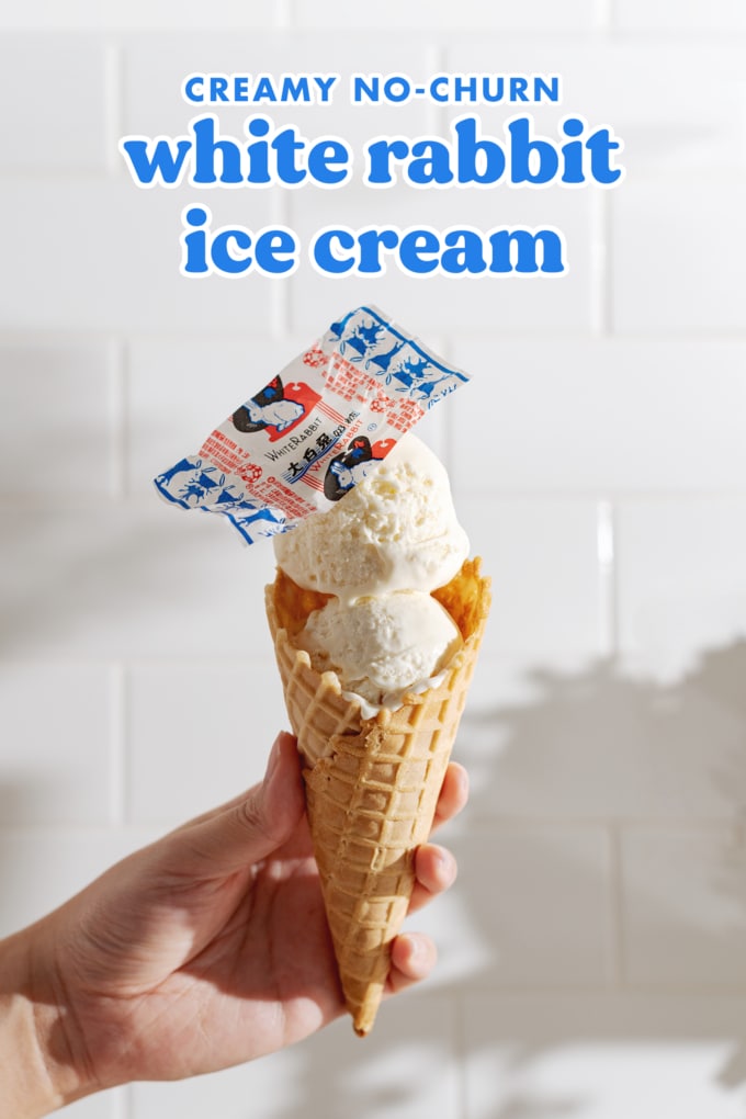 Hand holding an ice cream cone with two scoops of ice cream and white rabbit candy wrapper on top.