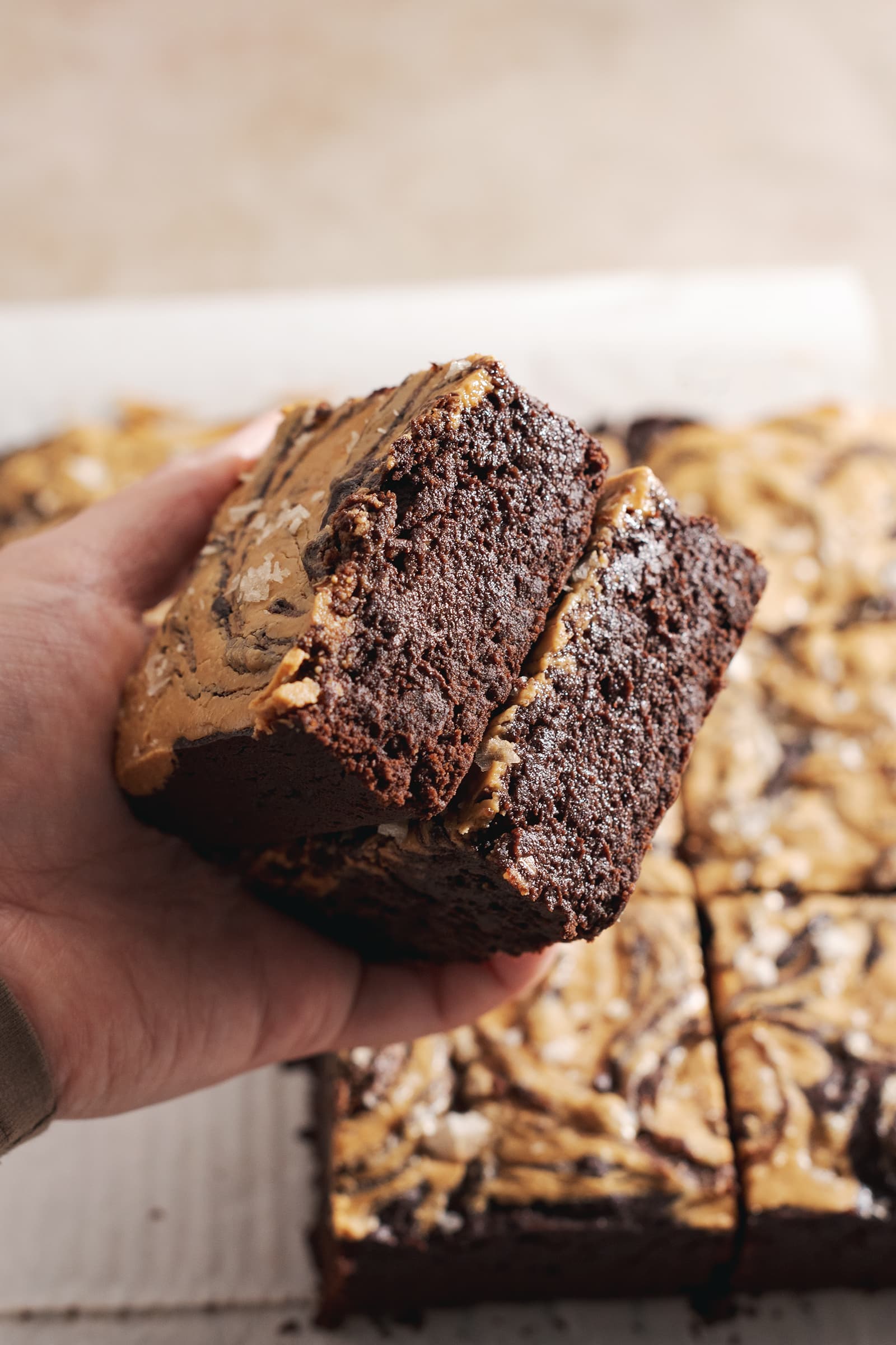 Hand holding two brownie slices to show the moist and fudgy sides.