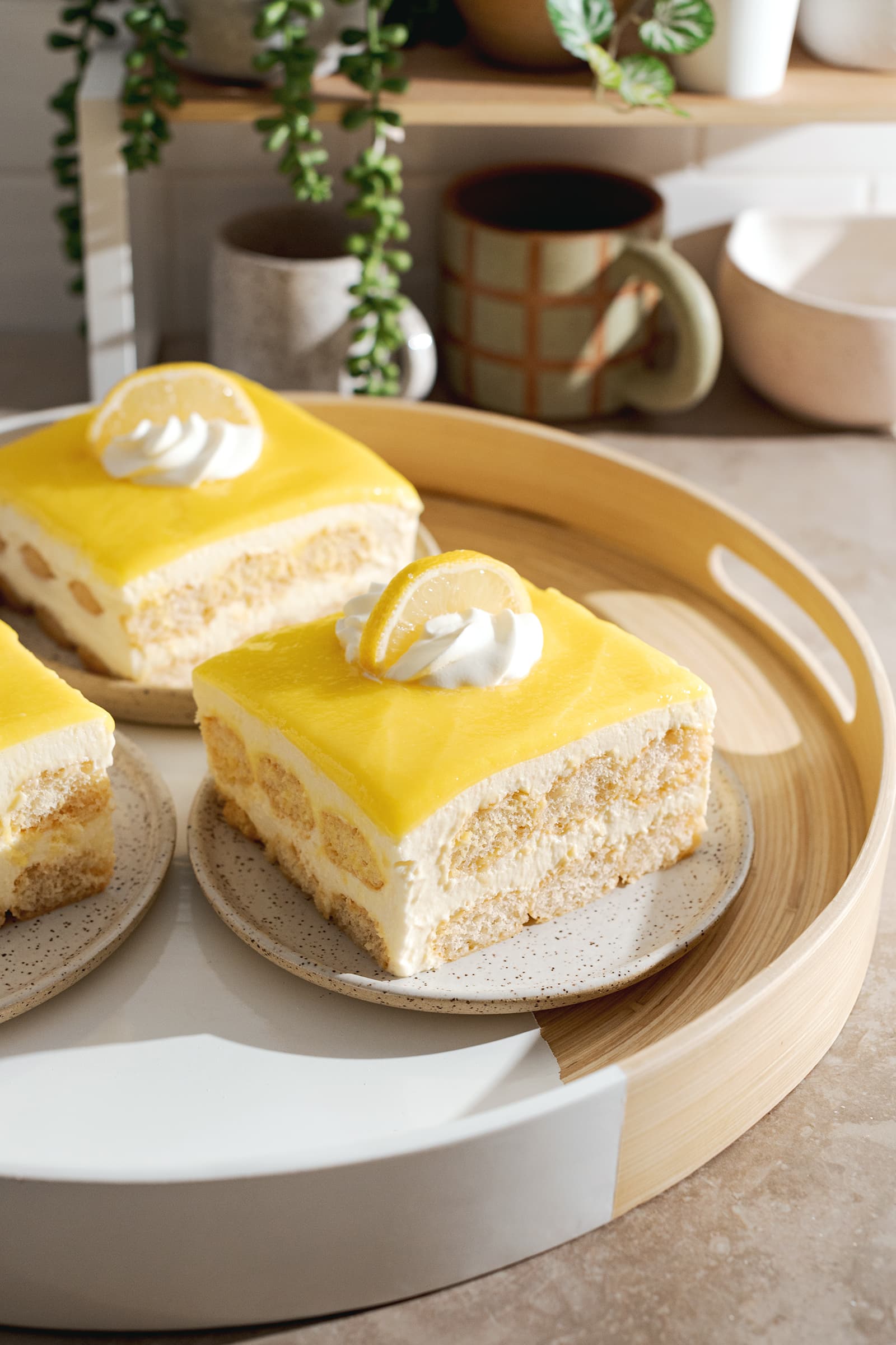 Square slices of limoncello tiramisu on a round tray with layers of ladyfingers, mascarpone, and lemon curd.