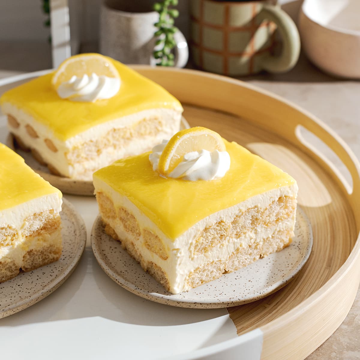 Square slices of limoncello tiramisu on a round tray with layers of ladyfingers, mascarpone, and lemon curd.