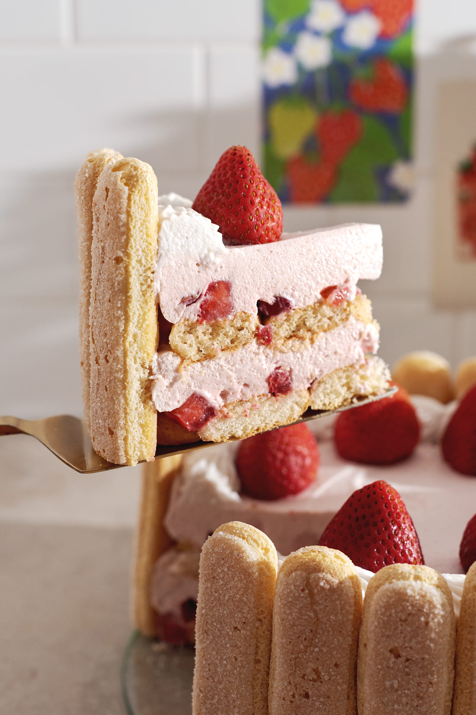 A slice of strawberry cake lifted from the rest of the cake.