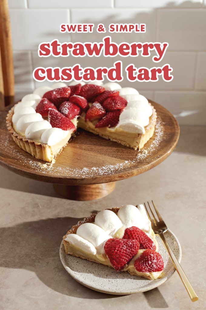A slice of strawberry custard tart on a plate in front of the rest of the tart on a cake stand.