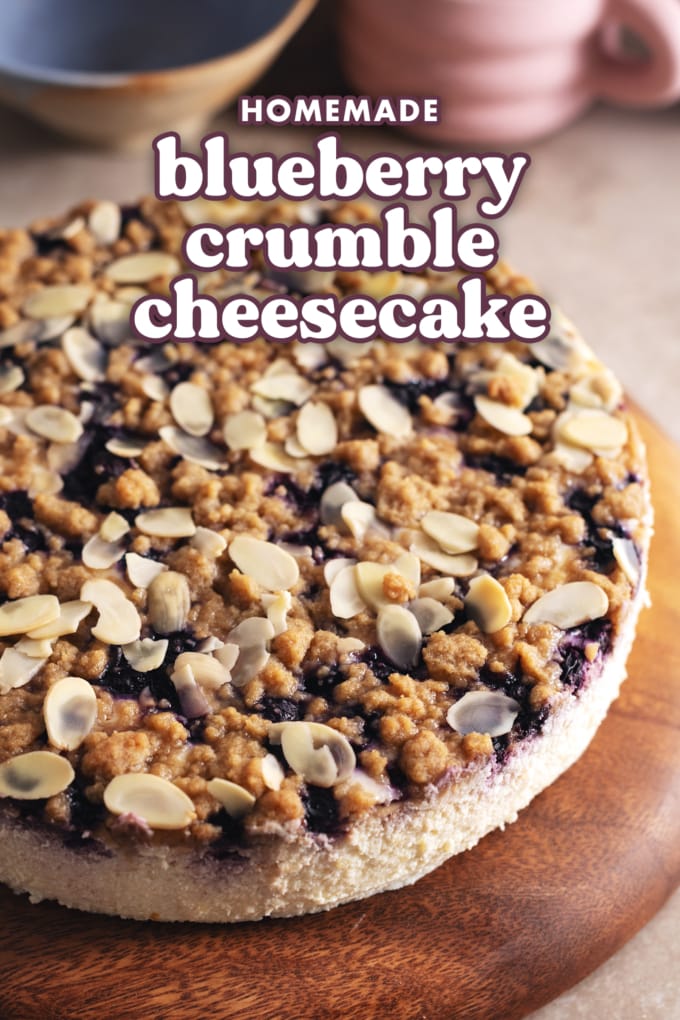 A blueberry crumble cheesecake on a wooden platter.
