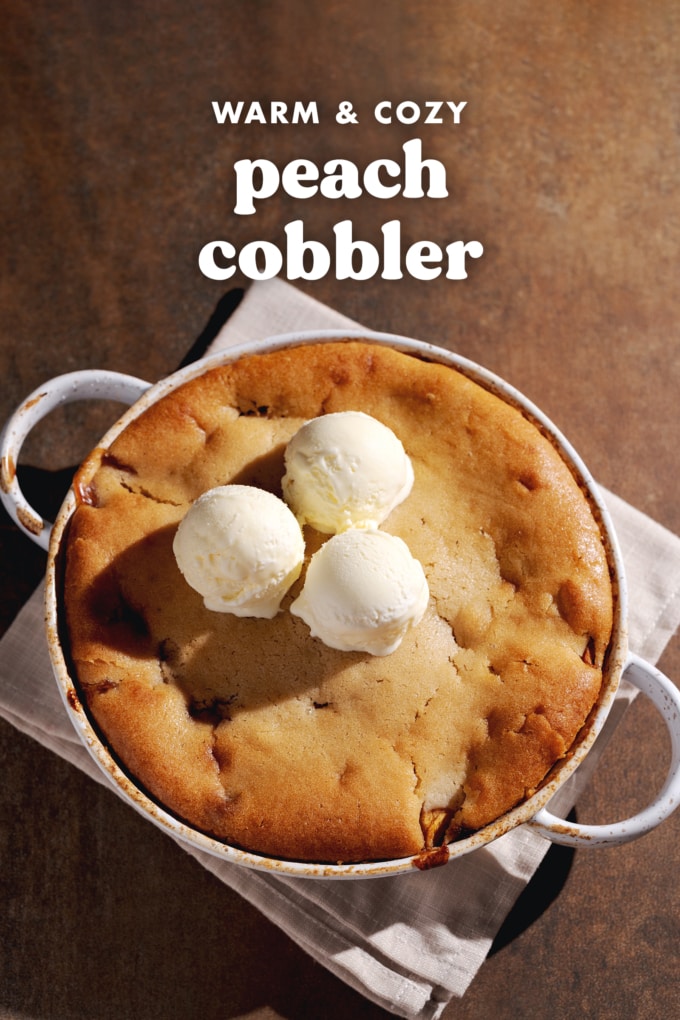 Top down view of a peach cobbler in a round baking dish with three scoops of ice cream on top.