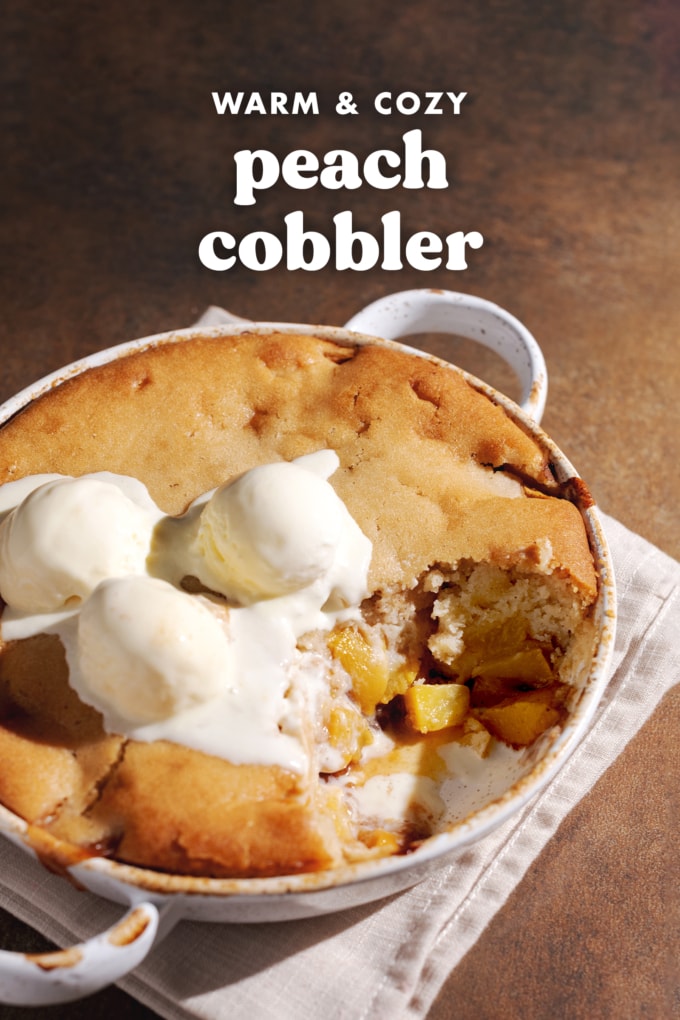 A dish of peach cobbler with a scoop taken out of it to show the peach filling inside.