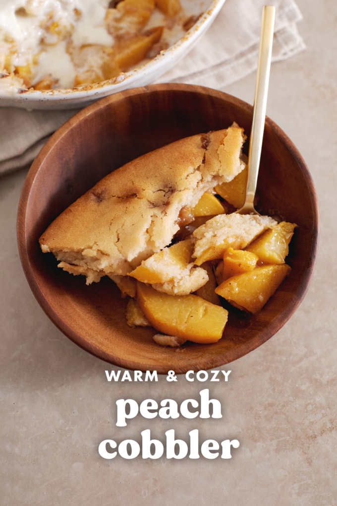 A slice of peach cobbler in a wooden bowl with a spoon.