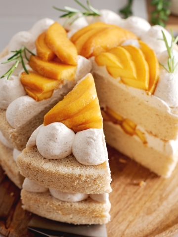 A slice of peach cake cut from the rest of the cake resting on a cake server.