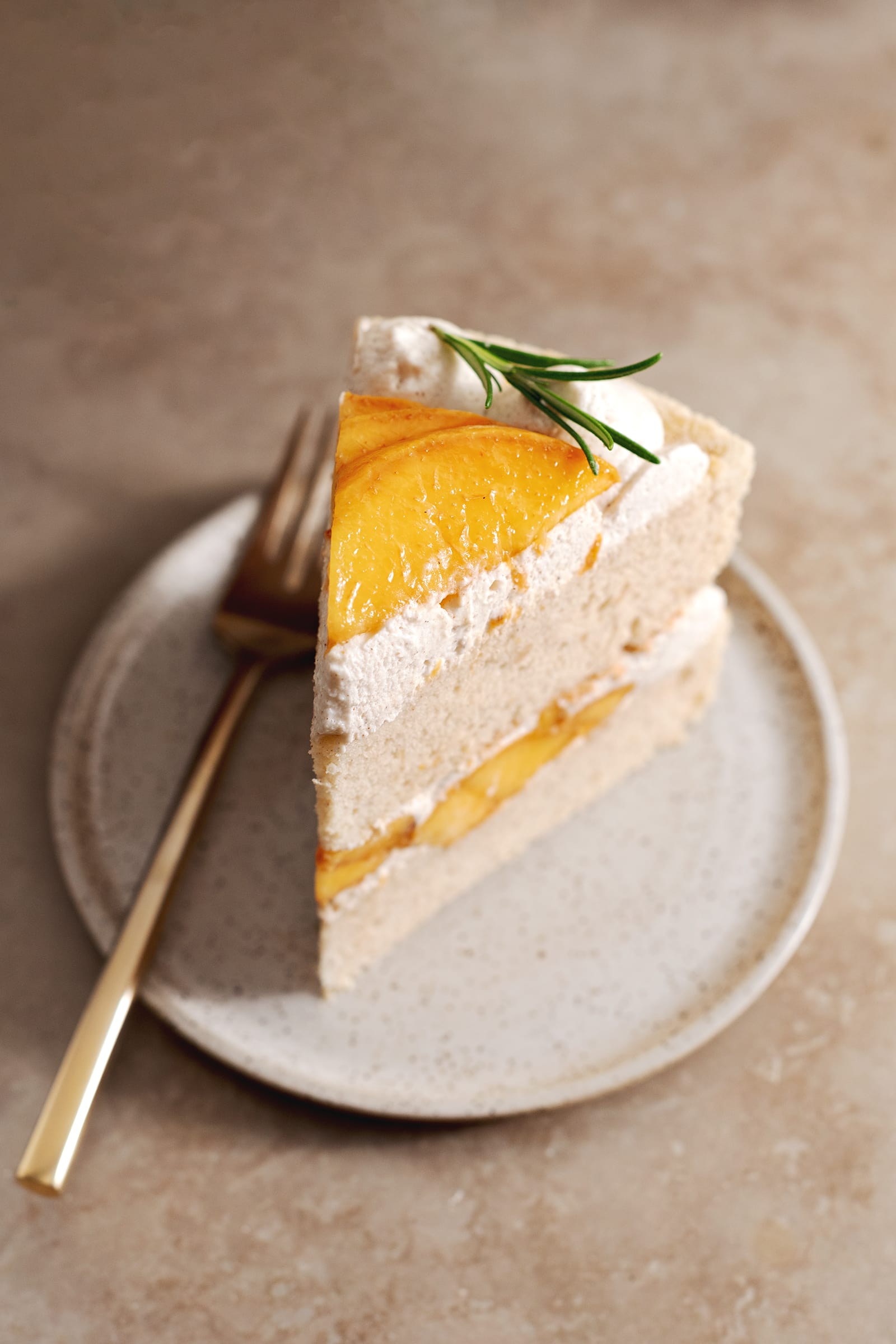A slice of peaches and cream cake on a plate with a fork next to it.
