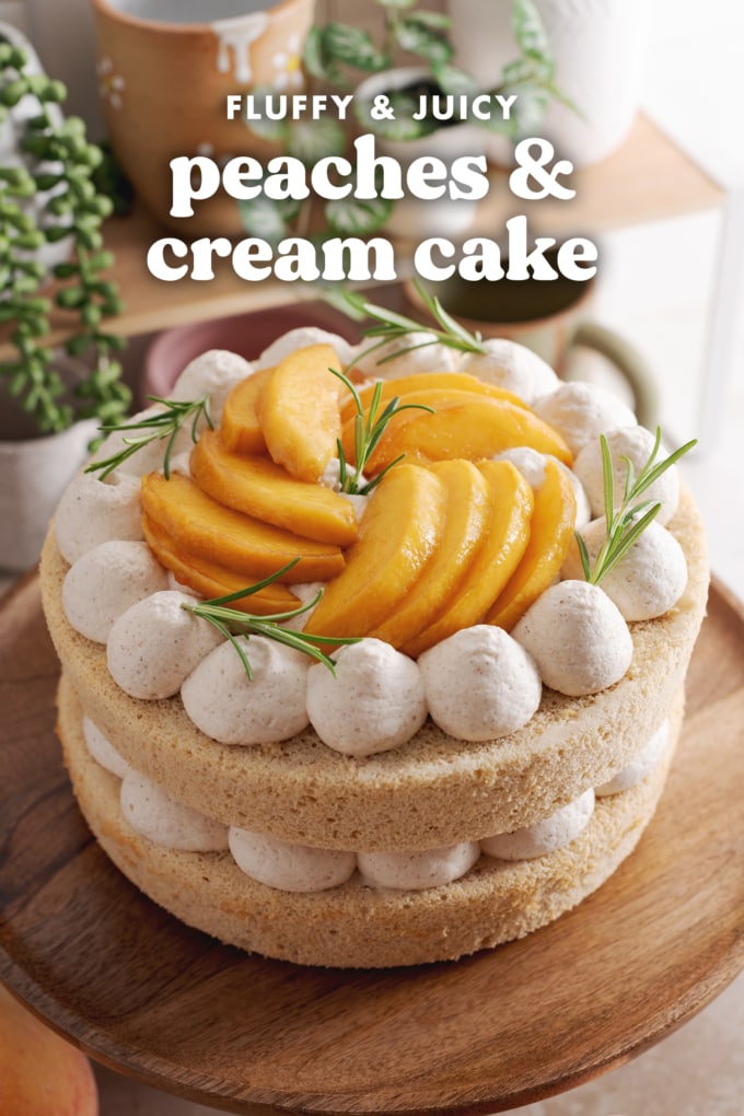 A cake topped with peach slices and dollops of whipped cream on a wooden cake stand.