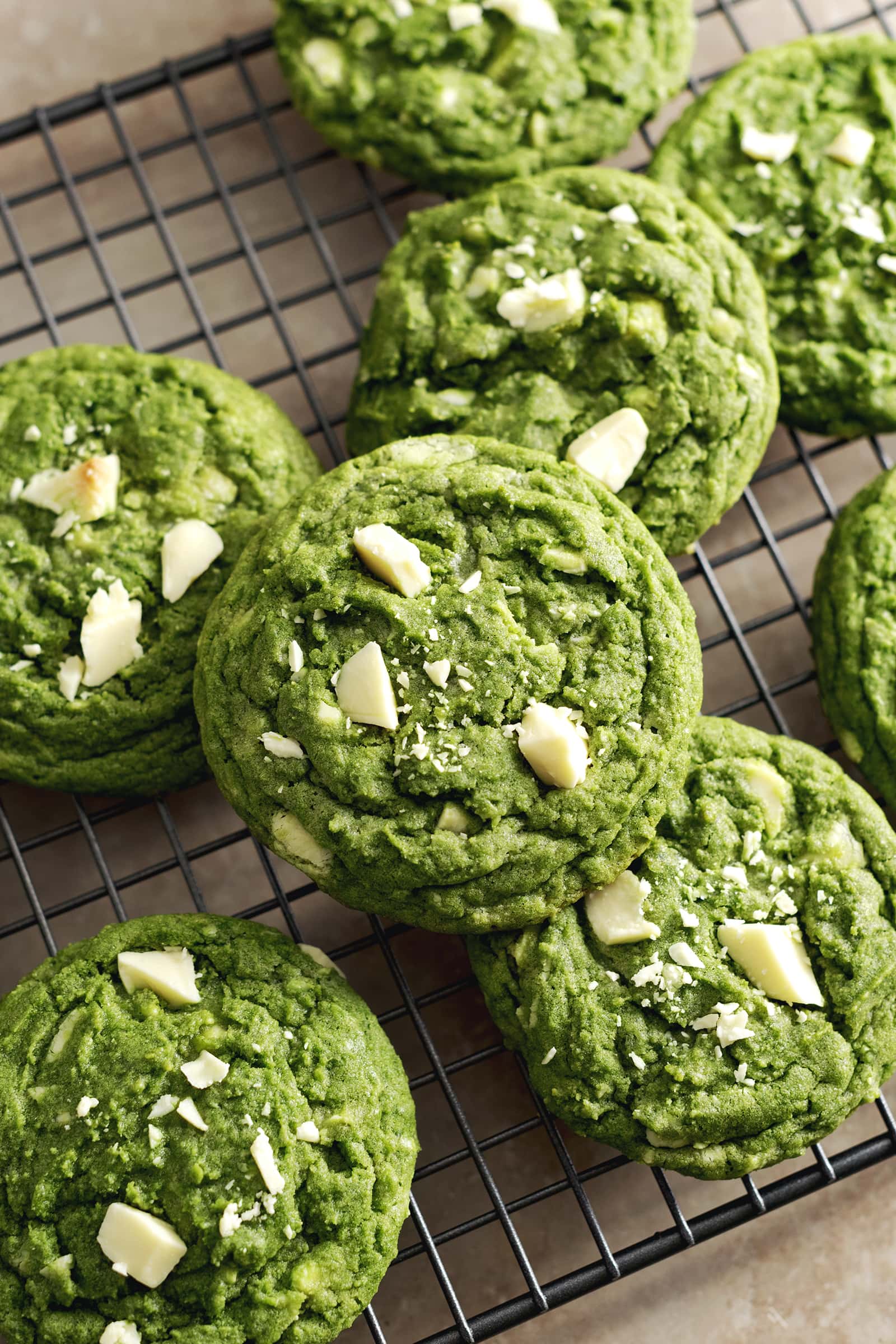 Matcha white chocolate cookies stacked on a wire rack.