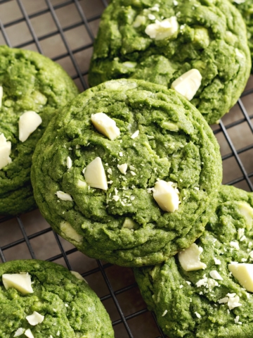 Matcha white chocolate cookies stacked on a wire rack.