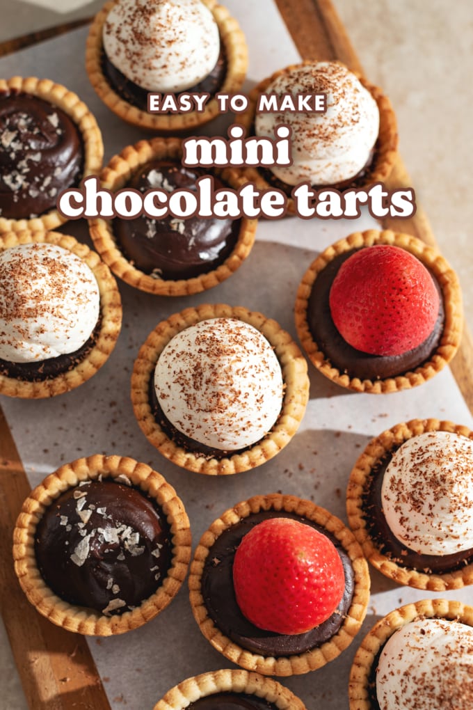 Top down view of chocolate tarts scattered on a wooden platter.