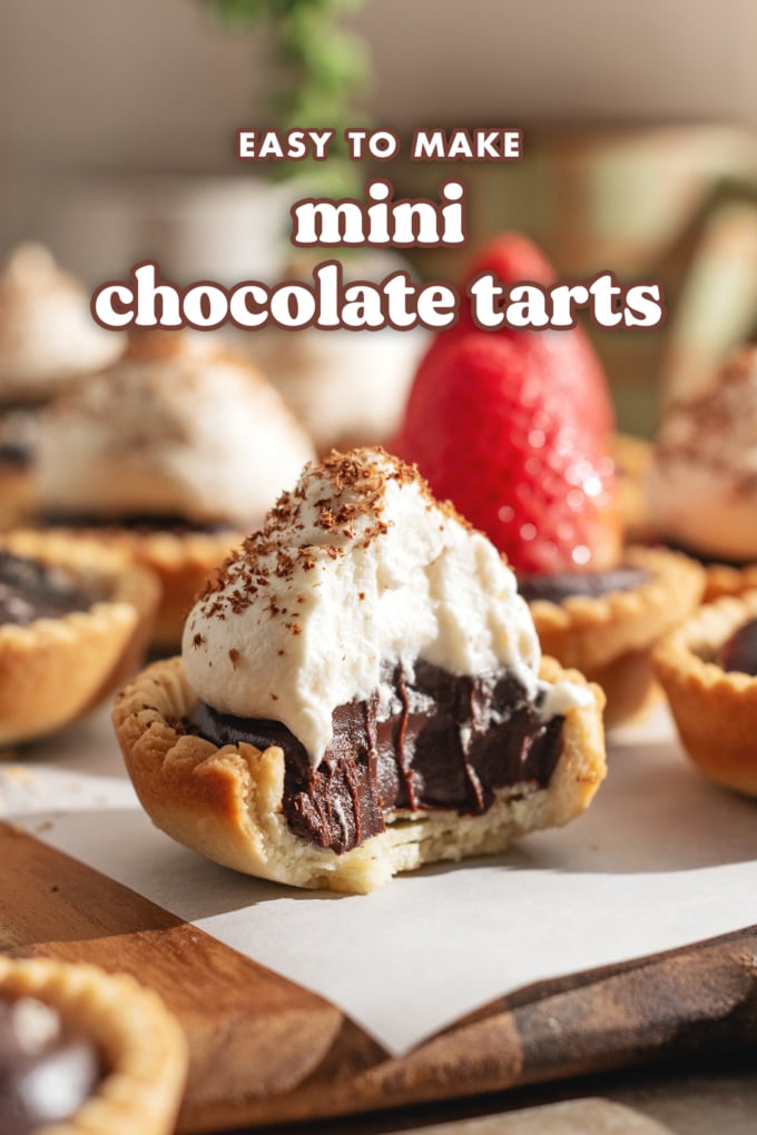 A mini chocolate tart with a bite taken out of it to show the chocolate ganache filling inside.