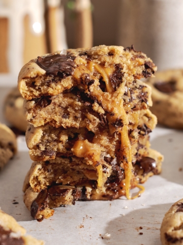 A stack of miso caramel cookies cut in half to show the goey caramel inside.