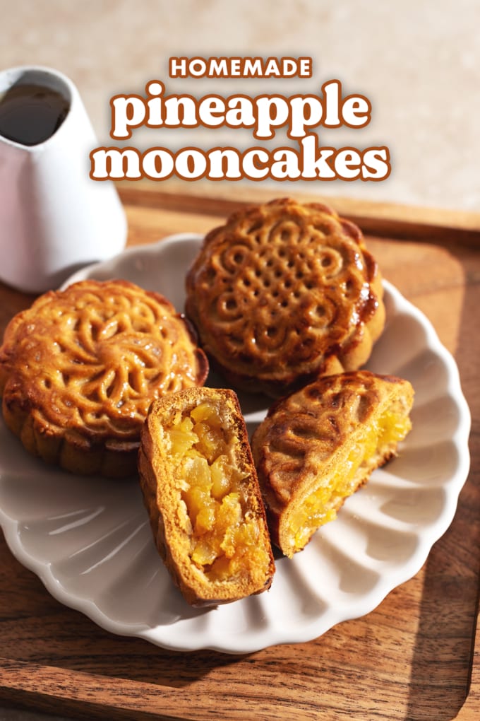 A pineapple mooncake cut in half on a plate with two other mooncakes.