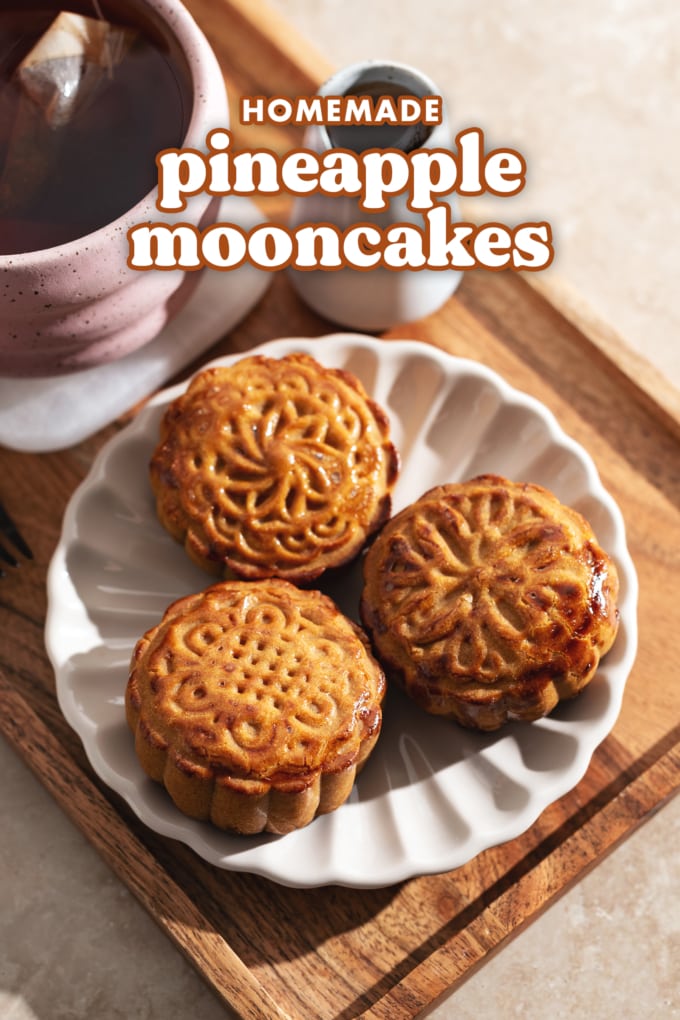 Three mooncakes on a plate on a tray with a cup of tea.