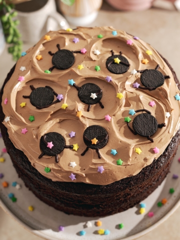 Mini oreo soot sprites and star sprinkles on top of chocolate buttercream on a chocolate cake.