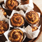 Several cinnamon roll muffins on a wooden platter.