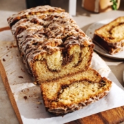 A loaf of cinnamon streusel bread with a slice cut off laying in front of it.