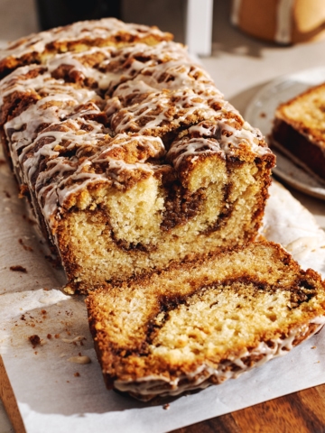 A loaf of cinnamon streusel bread with a slice cut off laying in front of it.