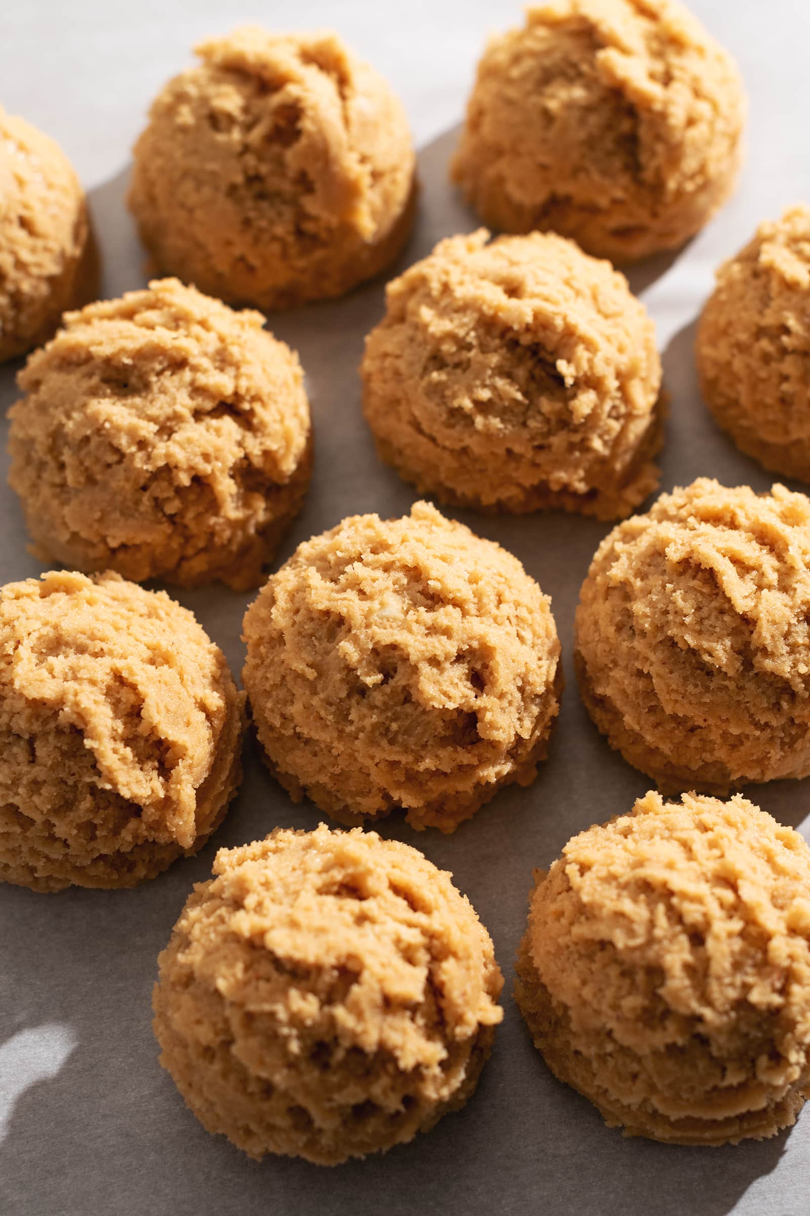 Balls of cookie dough lined up on parchment paper.