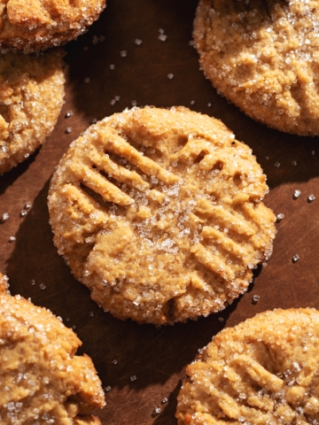 Overhead view of peanut butter miso cookies scattered on a wooden board.