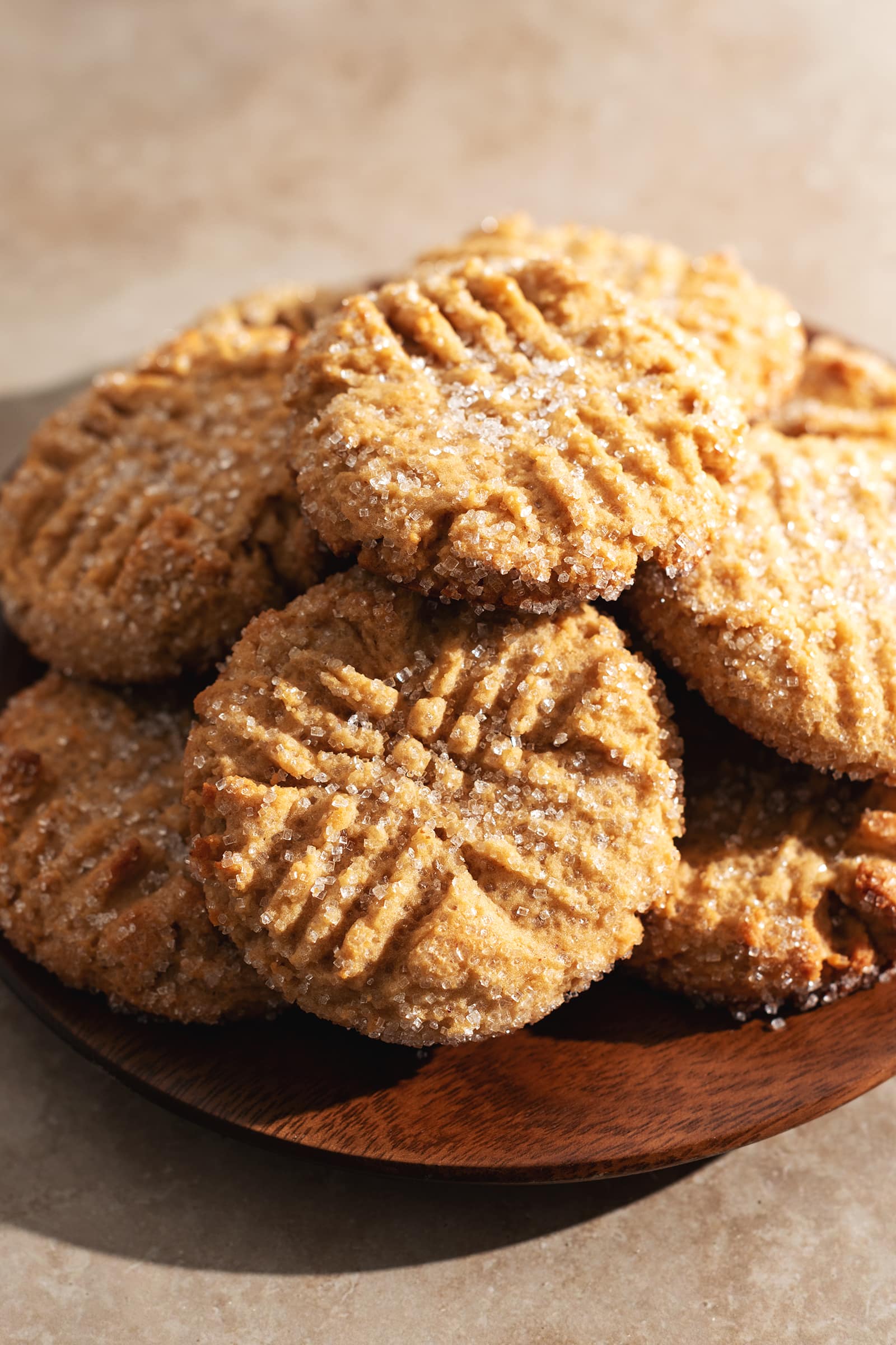Cookies piled on top of a wooden plate.