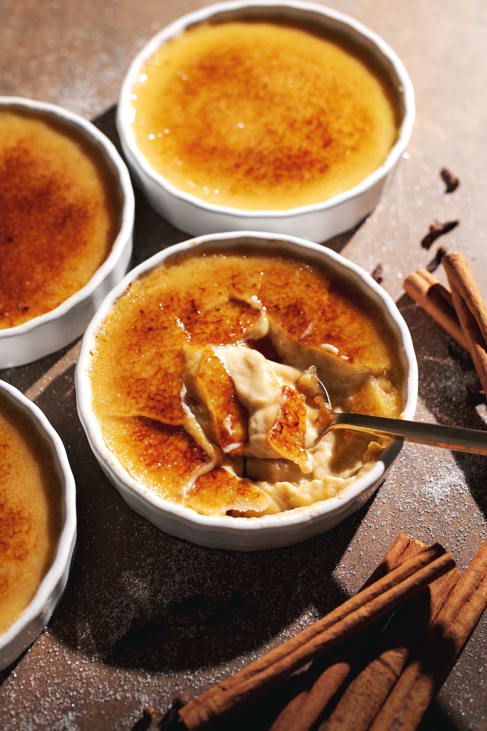 A spoon resting in a ramekin of cracked pumpkin crème brûlée.