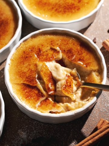 A spoon resting in a ramekin of cracked pumpkin crème brûlée.