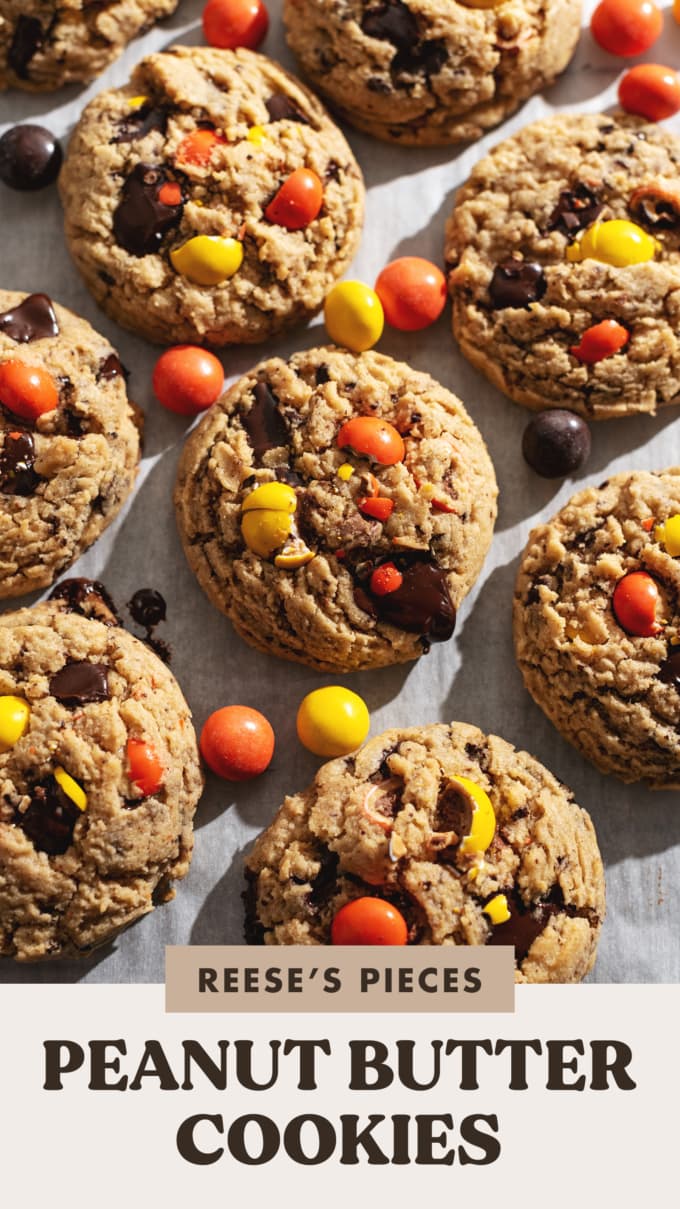 Cookies and reese's pieces candy scattered on parchment paper.