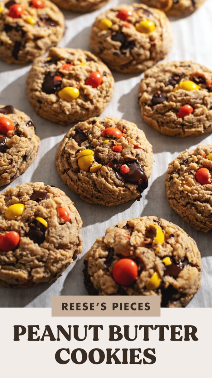 Cookies topped with chocolate and reese's pieces candy on parchment paper.