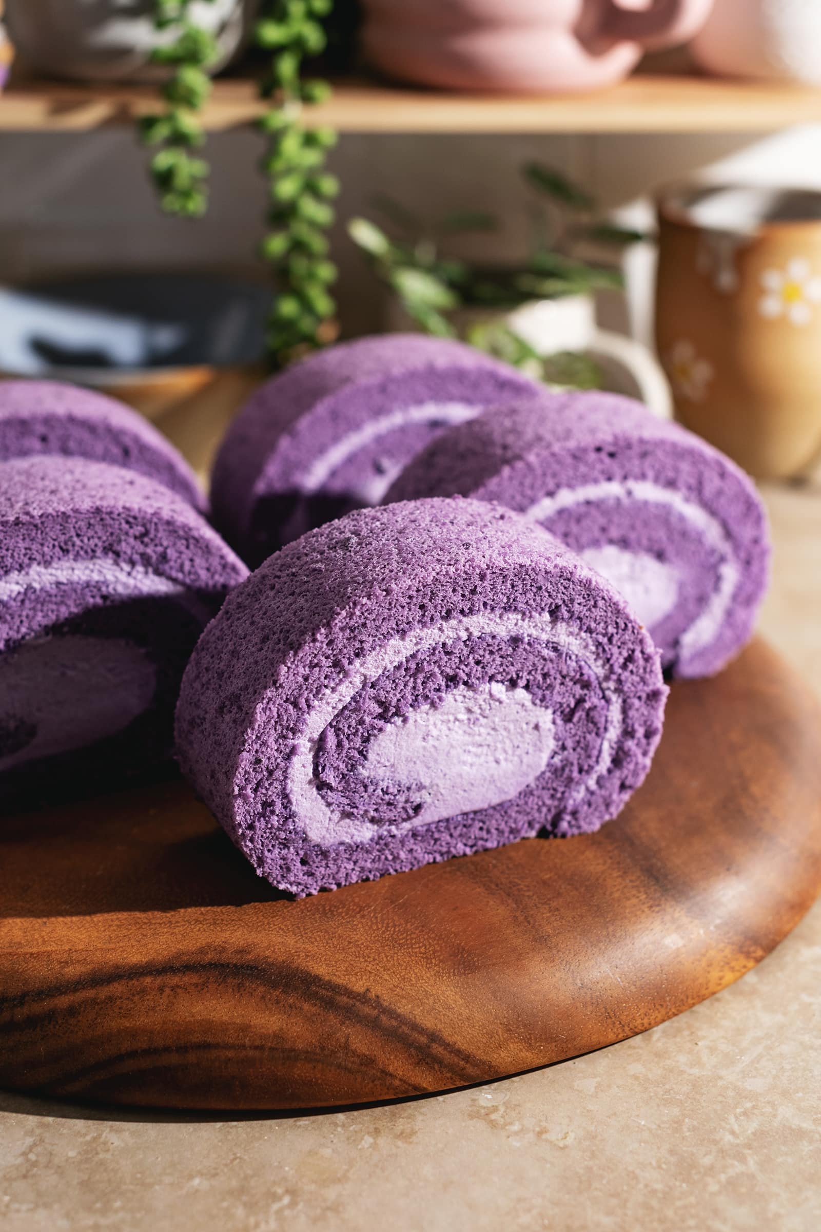 Slices of ube cake rolls lined up on a wooden platter.