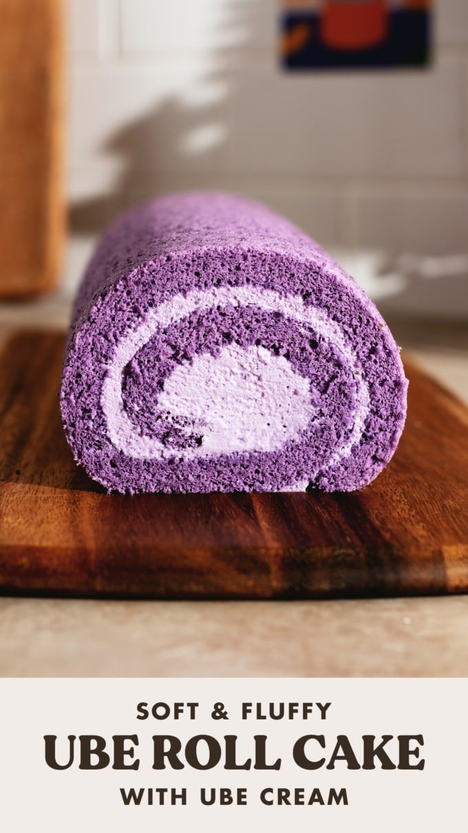 Cross section view of a purple ube roll cake on a wooden board.