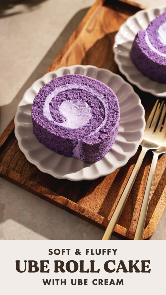 A slice of ube roll cake on a scalloped plate on a wooden tray.