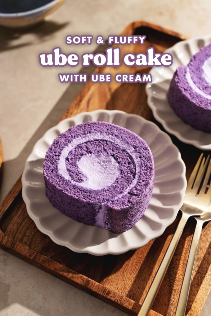 A slice of ube roll cake on a scalloped plate on a wooden tray.