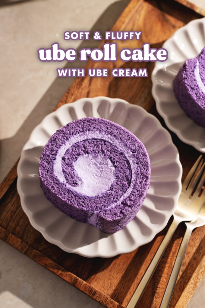 Top down view of a slice of ube roll cake on a scalloped plate on a wooden tray.